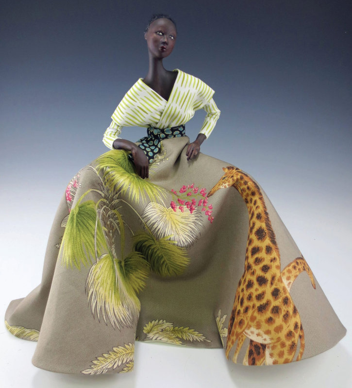 Gracie by Cindee Moyer. Figure of a black-skinned woman in a colorful dress with voluminous skirt painted with foliage and giraffes.