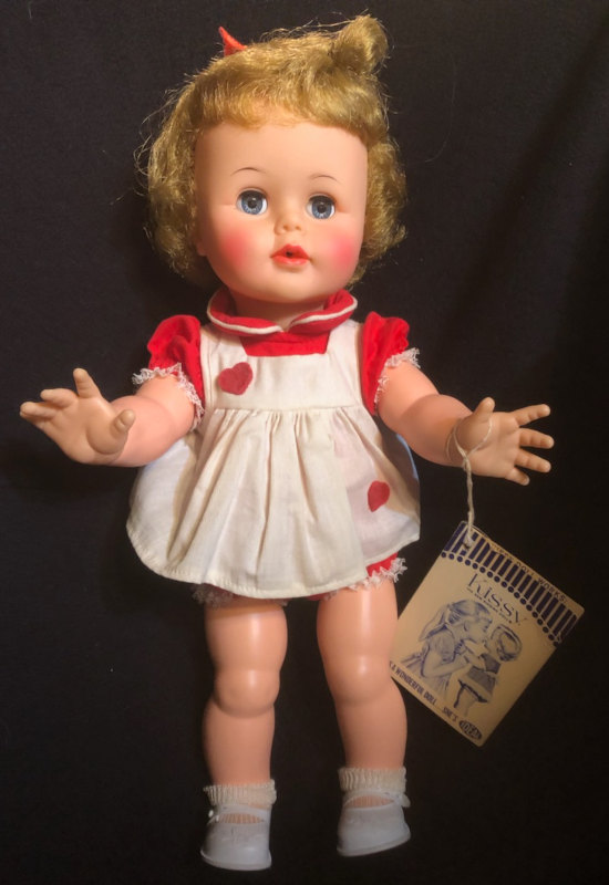 Photo of a Tiny Kissy doll with wrist tag. The special wrist tag is hard to find today. When you squeezed Tiny Kissy's arms together, her mouth puckered and gave you a kiss!