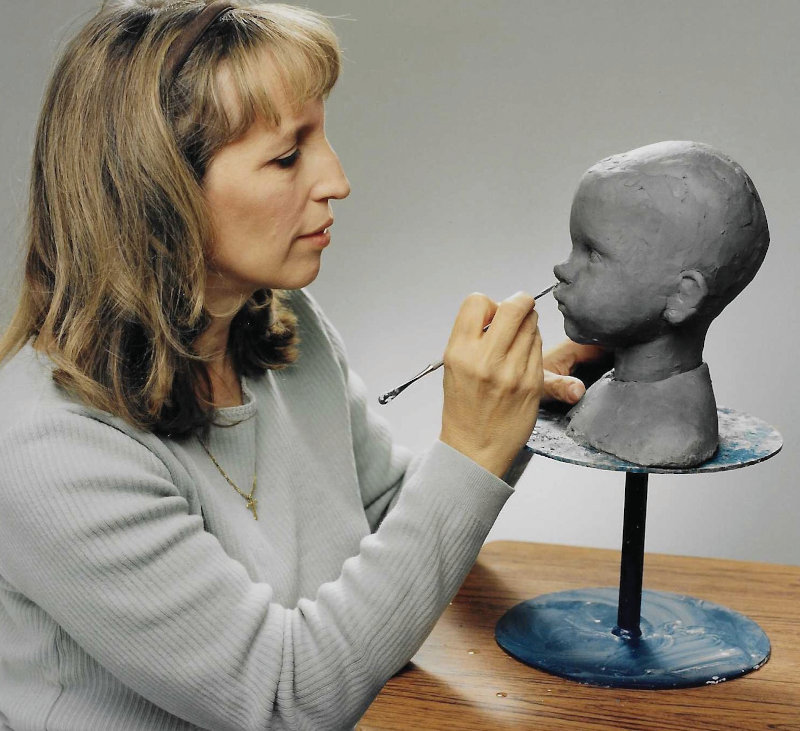 Dianna Effner in profile, photographed while working on the sculpt of a child's head.