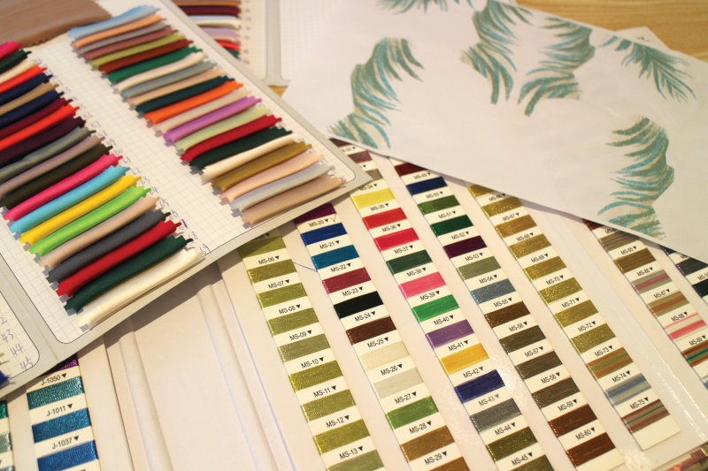 Fabric samples in different colors and prints next to a variety of embroidery thread samples.
