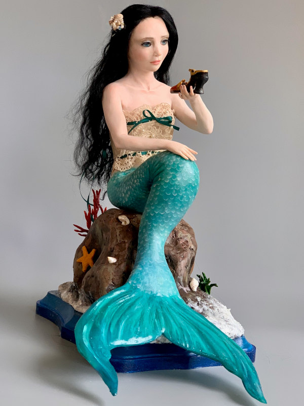Marina, 9 inches, is made from Cosclay polymer clay. She has hand-painted eyes, black mohair, a camisole of antique lace, and a tail with hand-cut scales.