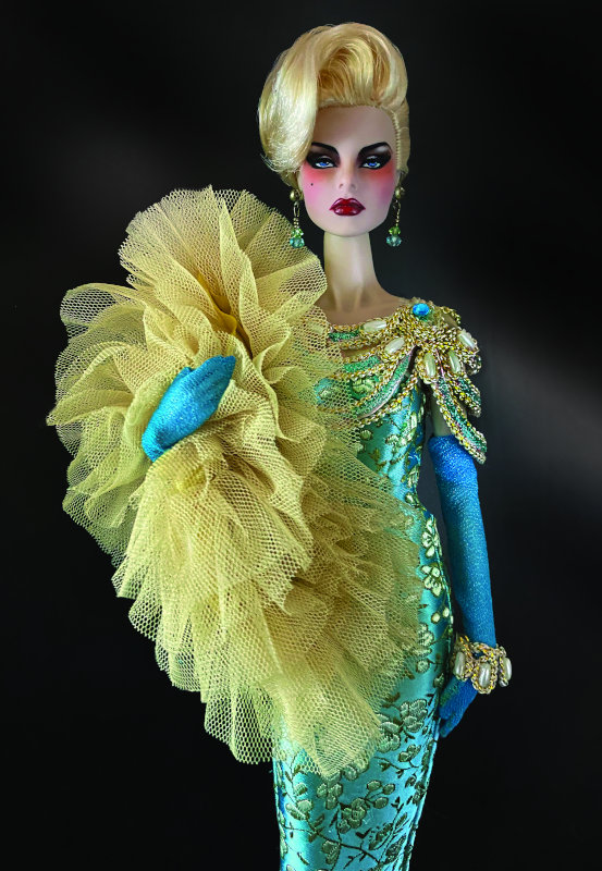 “Integrity Toys’ Fashion Royalty Agnes was my ‘Beast’ muse for this fitted silk brocade gown,” Lowenbein said. “Vintage gold roping with pearl and turquoise crystals adorn her shoulders and bracelet. She wears semi-sheer opera-length gloves and a whimsical layered tulle wrap. Dennis Beltrán created the short side-parted hairstyle and the ‘fairytale runway’ repaint.”
