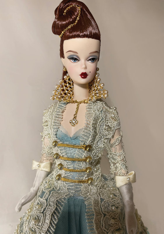 “Forbidden Love was an auction donation collaboration with my friend Seth Hanson for the 2019 Grant-A-Wish ‘A Knight To Remember’ Doll Convention this year. Parisienne Pretty Silkstone Barbie wears a Medieval inspired pearl beaded and floral lace gifted to me from Paris, France. Her delicate gown made with a soft blue-gray tulle is finished with ivory satin mid-length gloves with pearl bows. Hair created and adorned by my friend Seth Hanson. Jeweled Elizabethan styled ruff by Isabelle Leprivey of Paris finished the look. Our French princess, Forbidden Love was honored to win a DAE Industry Award this year!”