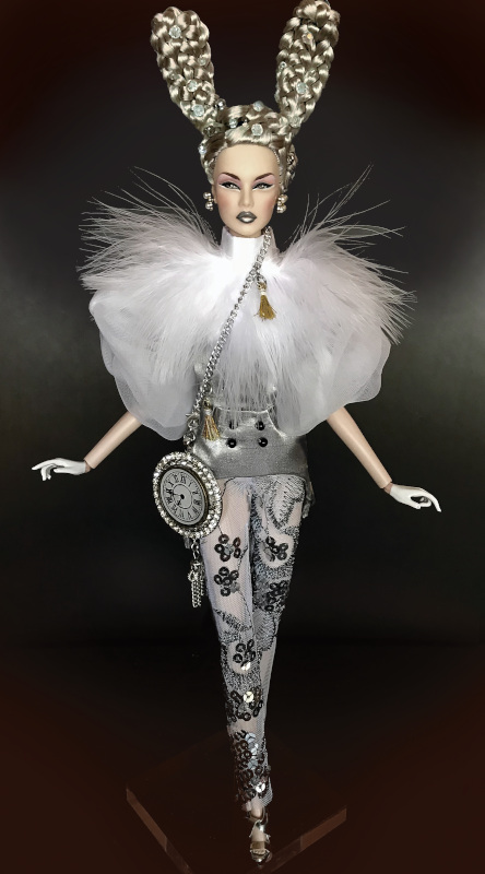 “White Rabbit was created for the Integrity Toys ‘Fairytale’ Convention doll design competition. Integrity’s NuFace Lilith’s unique silver rabbit-ear hair was created and bedazzled by Dennis Beltrán for this ‘fantasy couture’ character from Alice in Wonderland. Sheer chiffon top with balloon sleeves topped with long marabou feathers. A satin four-button corset tops sheer embroidered pants. Silk tassels hang from her ‘clock’ purse. We were honored to win Integrity Toys’ People’s Choice and Judges’ Choice Awards.”