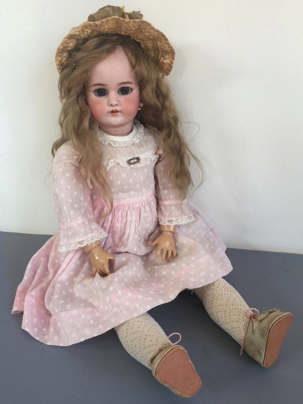 The repaired doll, now with an antique wig and dressed in vintage clothing.