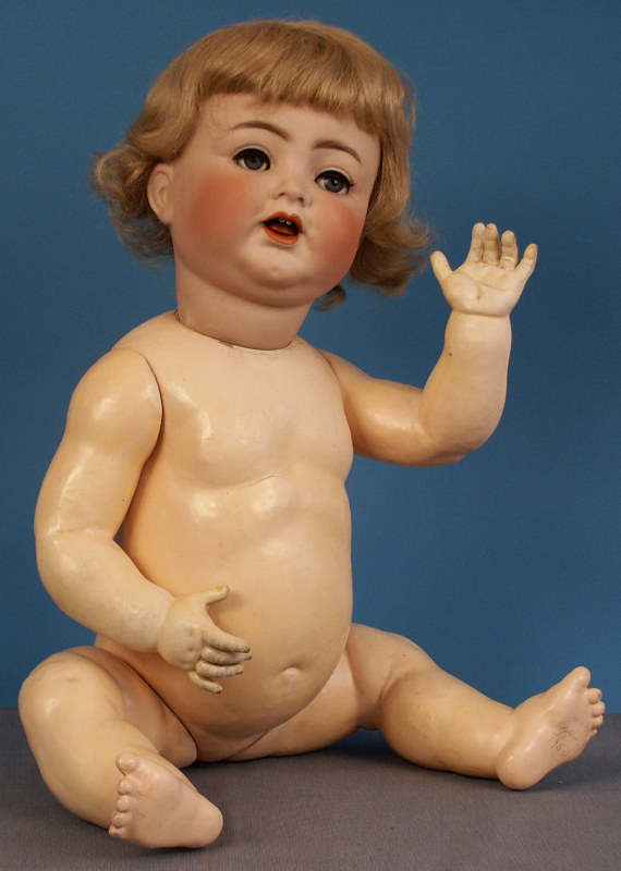 This K&R smiling character baby doll model 126 is unusually large at 29 inches. It features glass eyes, open mouth with teeth and tongue, and a wig on a composition baby body.