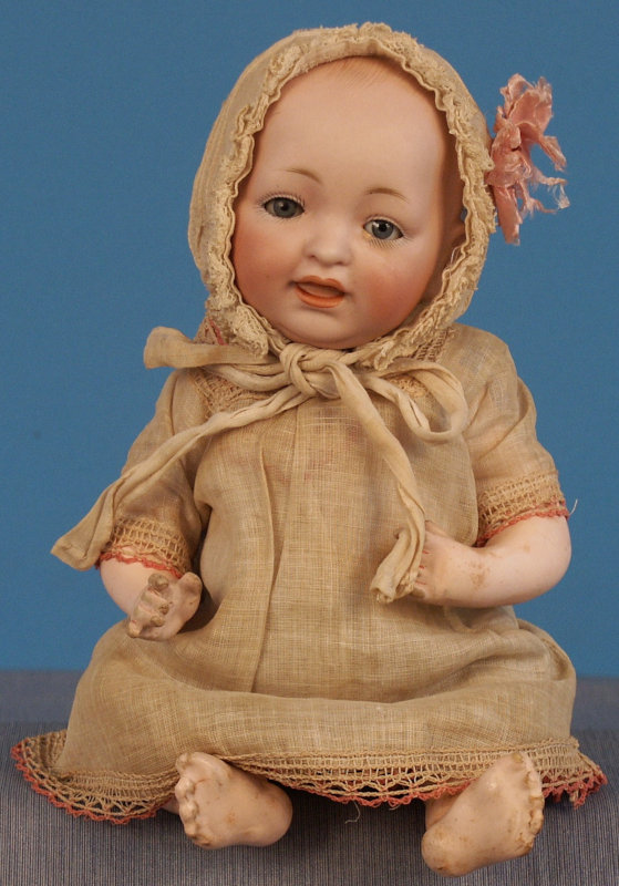 An 11-inch Kestner JDK character baby with glass sleeping eyes on a Kestner composition baby body with typical Kestner turned-in left arm.