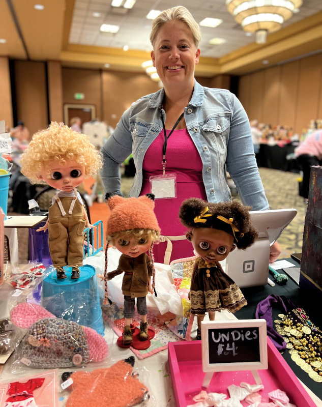Expo owner and organizer Casie Brabham stands at her sales table offering customized Blythe dolls along with doll outfits and accessories.