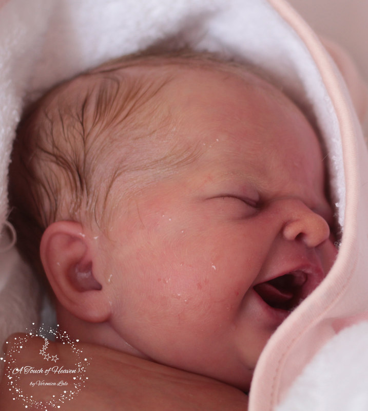 Realistic baby doll with eyes shut and mouth open in a yawn.