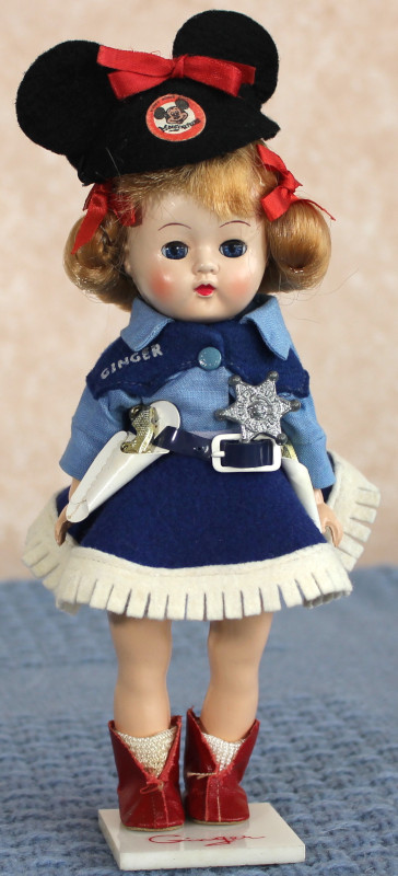 Plastic Ginger doll wearing Mickey Mouse Club hat, blue Western-style outfit with white trim, including star badge and toy pistol, and brown cowgirl boots.