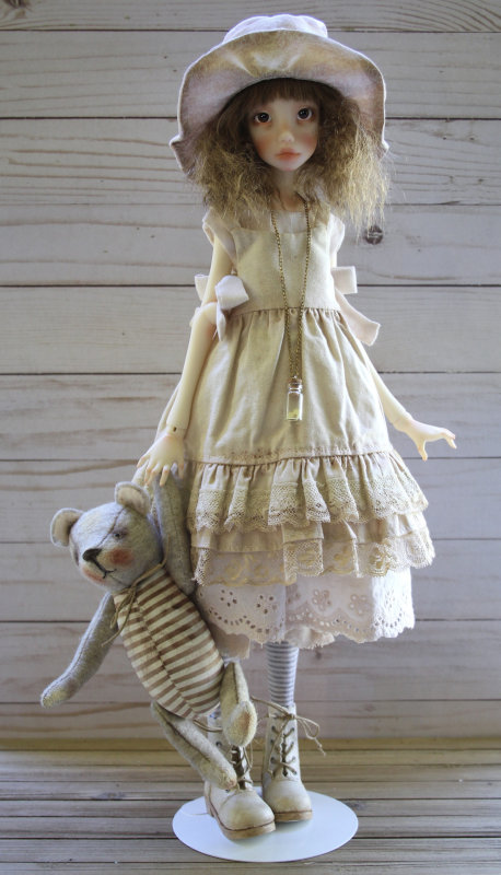 BJD of a teenage girl wearing an off-white dress and holding a teddy bear in one hand.