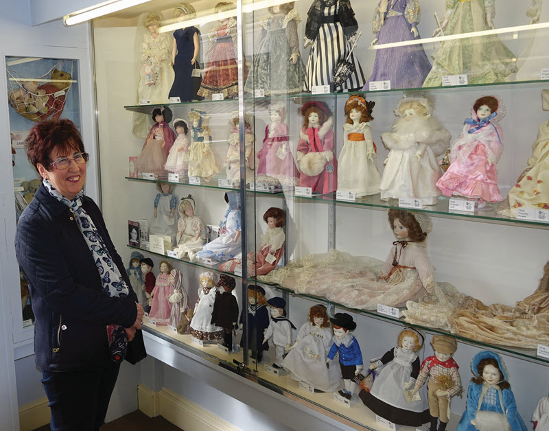 Chris Poulten poses with dolls she donated to a museum.