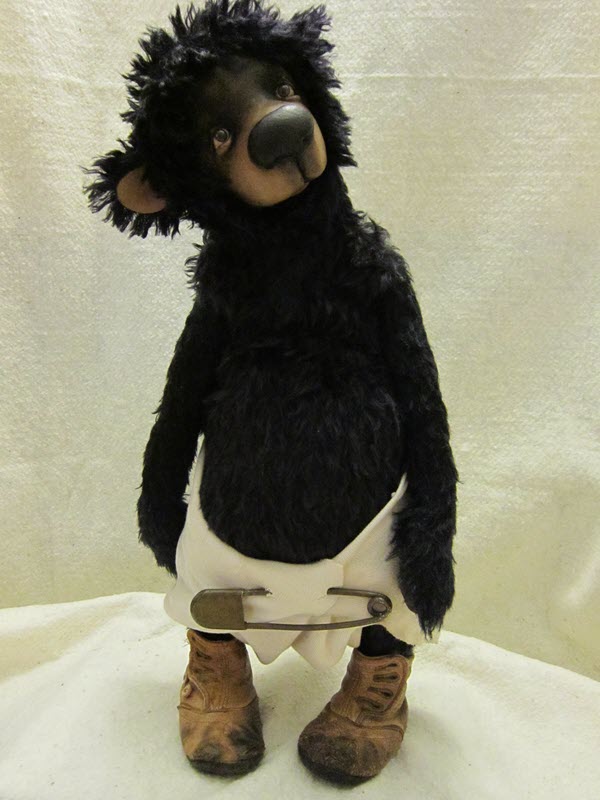 Black bear wearing a diaper with pin and antique-looking shoes
