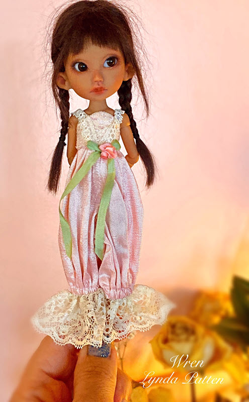 7-inch BJD has brown hair in side braids and wears a pink jumper with lace details.