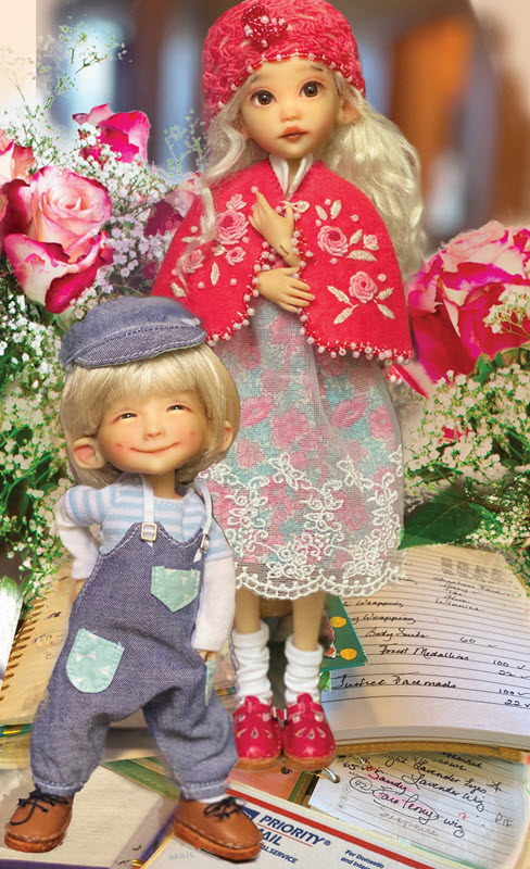 A female doll wearing a dress and capelet and a small male doll in overalls