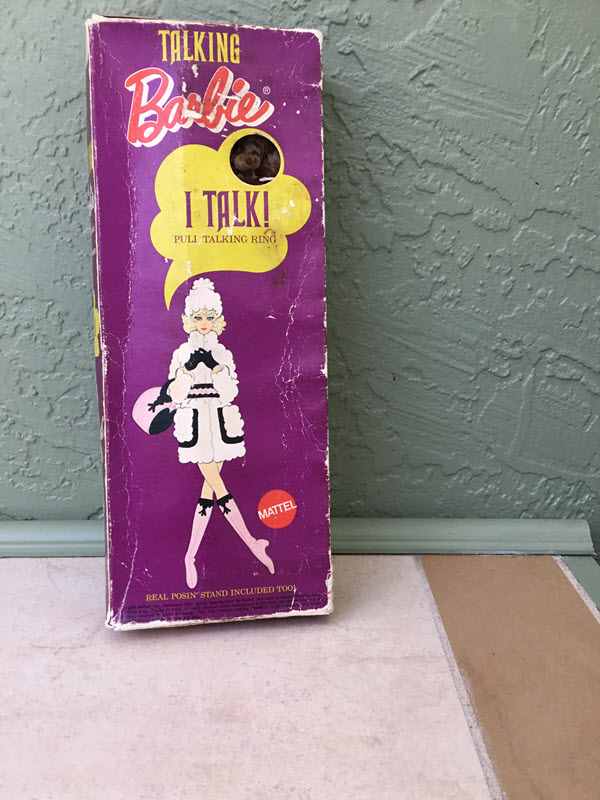 Purple box with an image of Barbie in one of her shareable fashions (coat, knee-high boots, black gloves, hat, and purse)