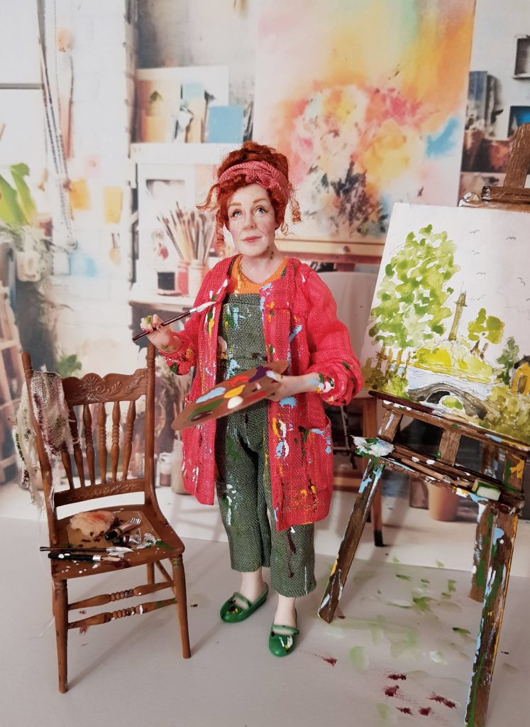 miniature doll artist with paint splattered clothes