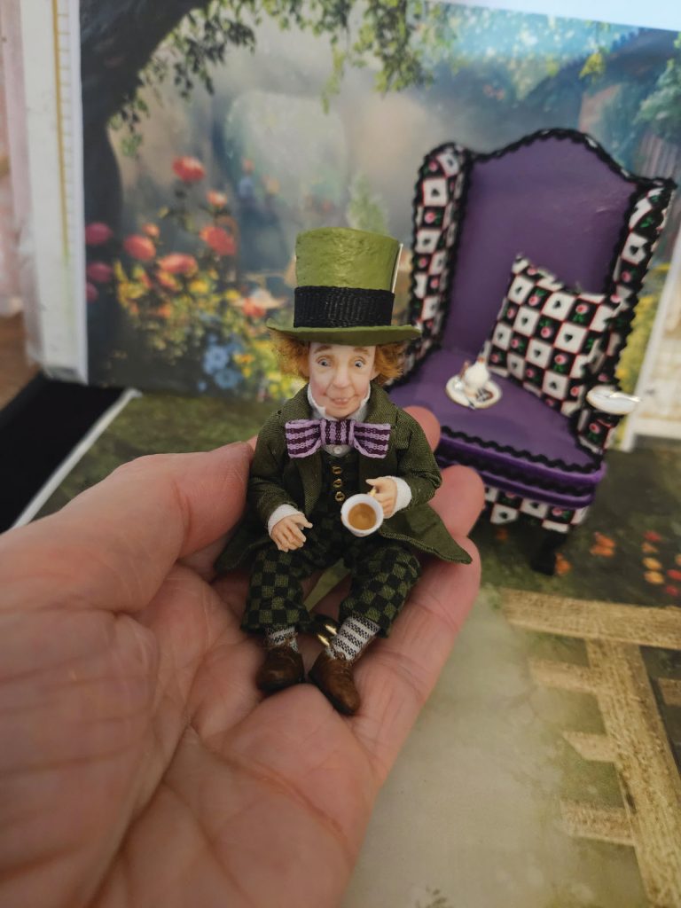 miniature mad hatter doll on artist's hand for perspective