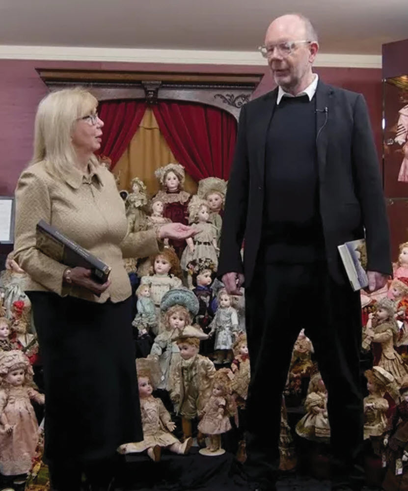 woman talking with a man with dolls in the background