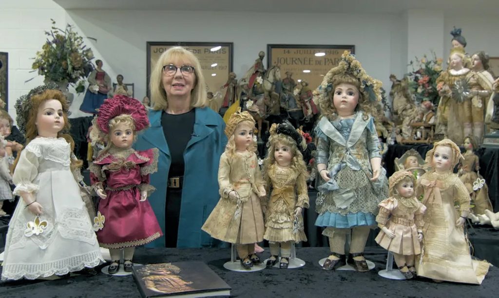 woman surrounded with dolls for doll auction