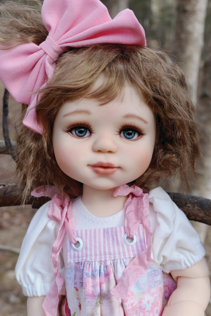 brunette doll with large pink hair bow and pink dress